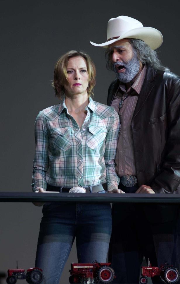 Eine Frau und ein Mann im Cowboyhut betrachten Spielzeugtraktoren.