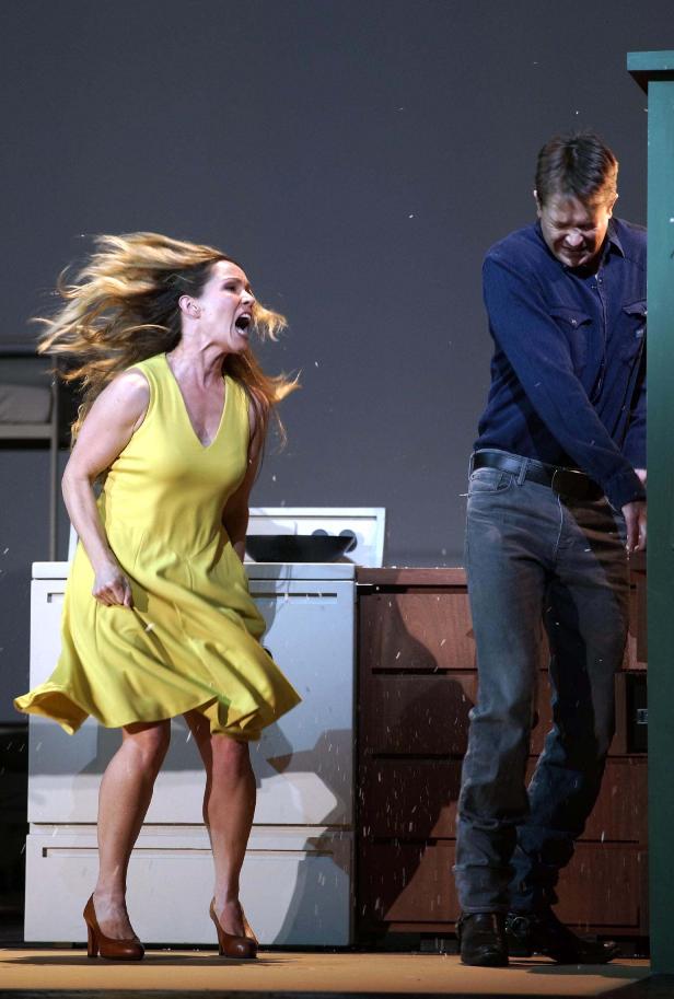 Eine Frau in einem gelben Kleid schreit einen Mann an, während es schneit.