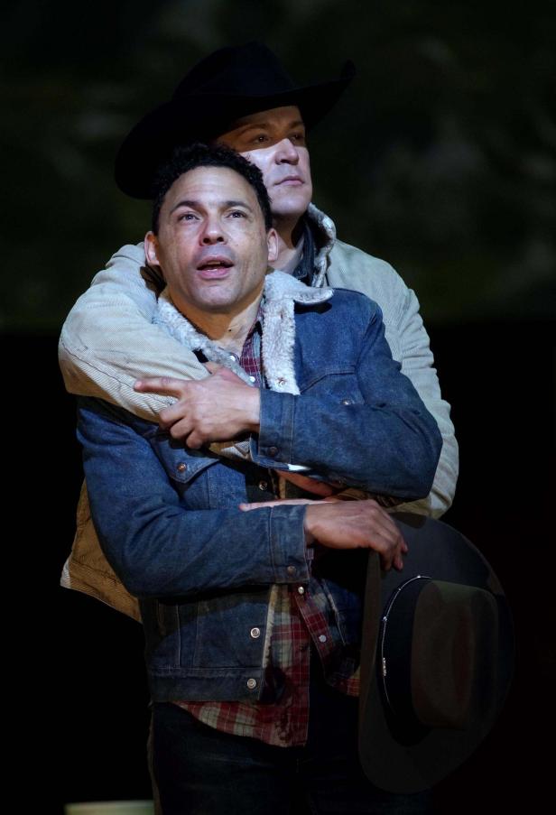 Zwei Männer mit Cowboyhüten umarmen sich.