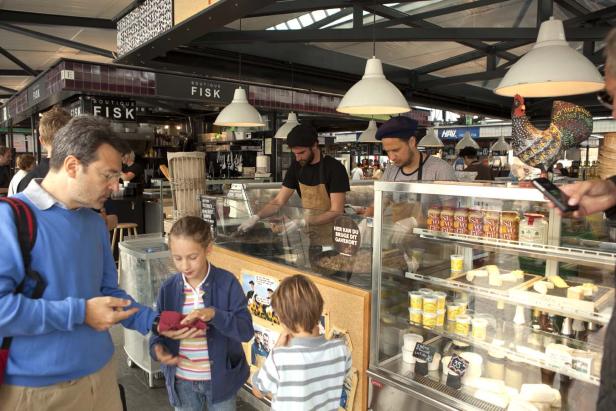 Eine Familie steht an einem Fischstand in einer Markthalle.