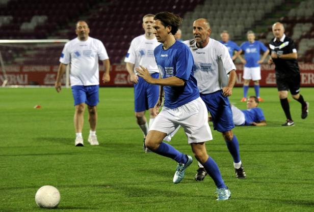 Ein Fußballspieler rennt mit dem Ball auf dem Spielfeld.