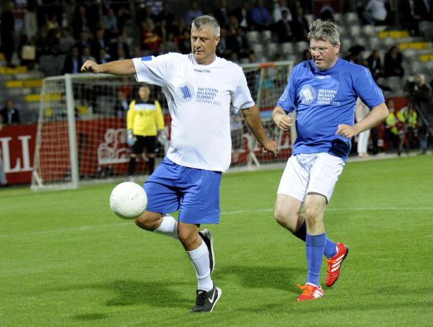 Zwei Männer spielen auf einem grünen Rasen Fußball.