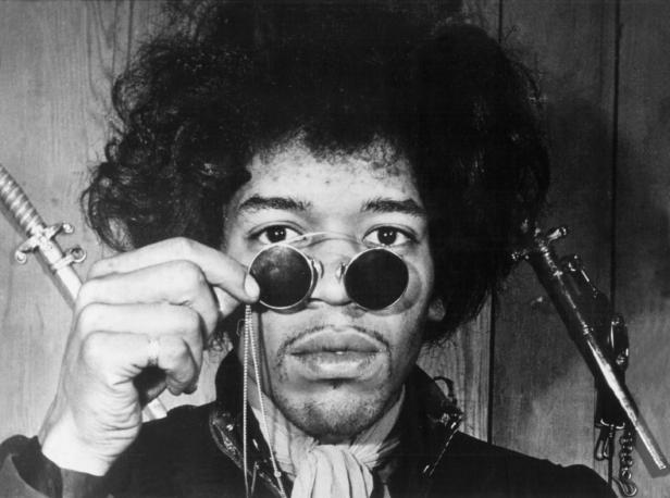 Ein Schwarzweißporträt von Jimi Hendrix mit runden Gläsern und zwei Schwertern im Hintergrund.