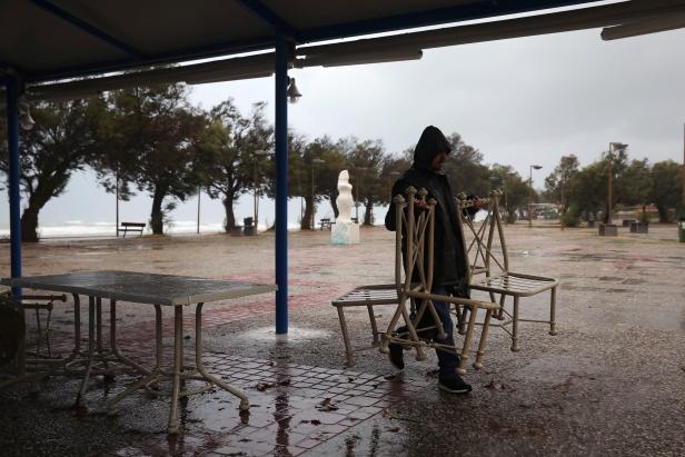 A man carries restaurant chairs in the village of Gastouni, as a rare storm known as a Medicane (Mediterranean hurricane), hit western Greece
