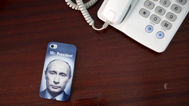 Ein Handy mit einem Bild von Wladimir Putin und der Aufschrift „Mr. President“ liegt neben einem Telefon.