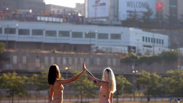 Zwei barbusige Frauen geben sich vor einer Stadtkulisse ein High-Five.