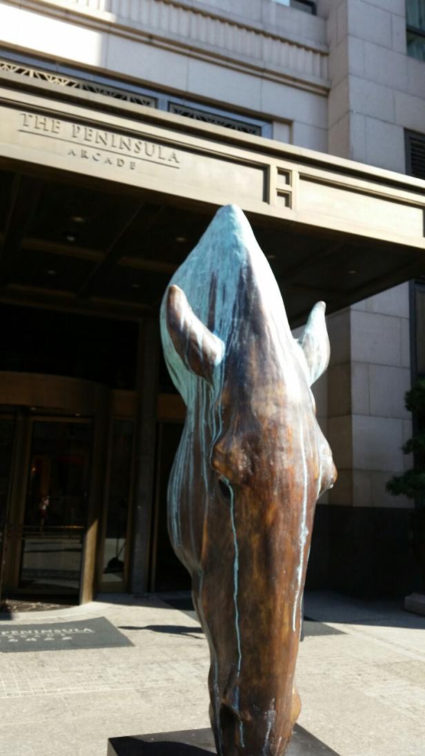 Eine Bronzeskulptur eines Pferdekopfes vor dem Peninsula Arcade Gebäude.