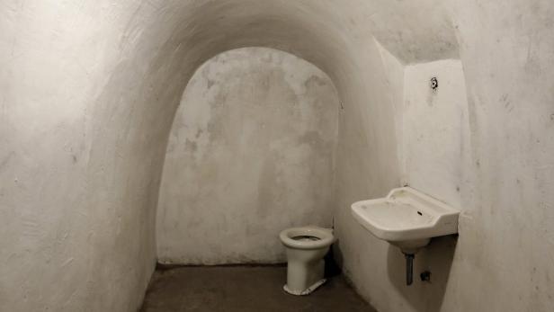 Eine kleine Zelle mit Toilette und Waschbecken.