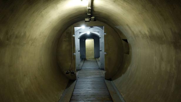 Ein Tunnel mit einer Holzboden führt zu einer Tür am Ende.