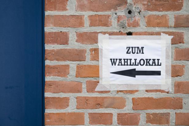 Zettel mit der Aufschrift "Zum Wahllokal" hängt an einer Wand. 