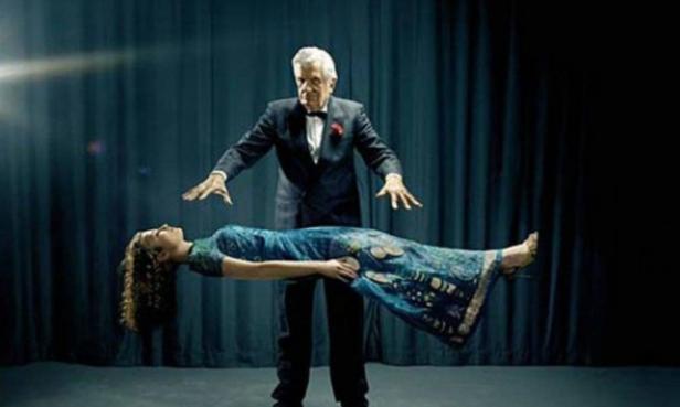 Ein Magier lässt eine Frau auf der Bühne schweben.