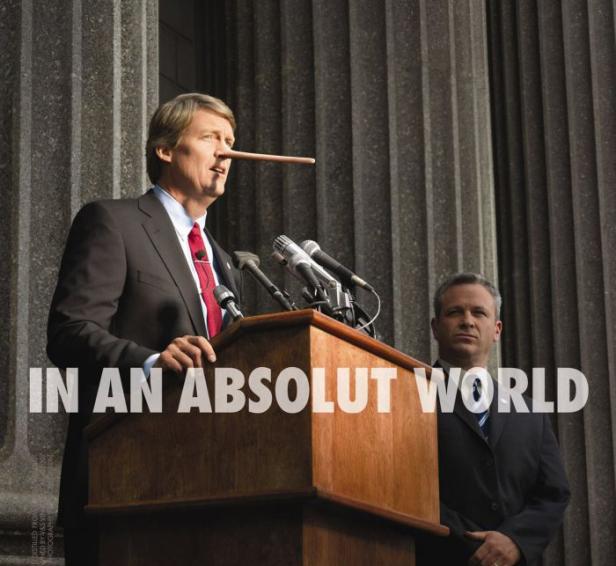 Ein Mann mit einer langen Nase steht an einem Rednerpult vor Säulen.