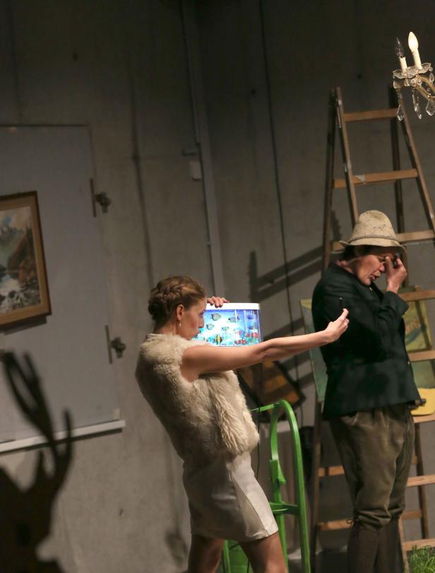 Eine Frau hält ein Aquarium, während ein Mann mit Hut daneben steht.