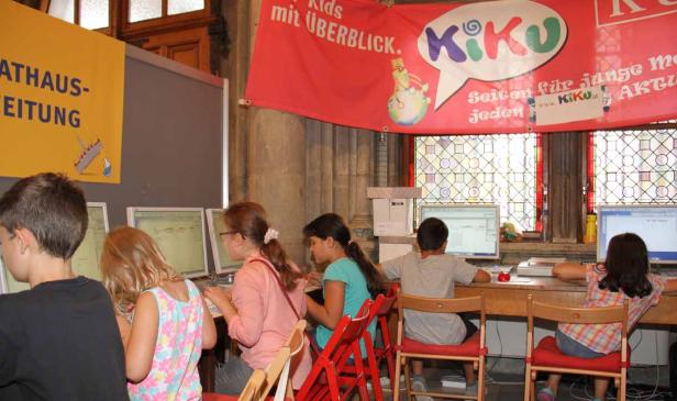 Kinder sitzen an Computern unter einem Banner für „KiKu – Kids mit Überblick“.
