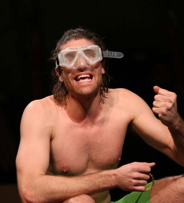 Ein Mann mit Taucherbrille und freiem Oberkörper jubelt.