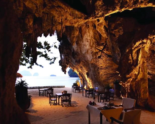 Ein Restaurant in einer Höhle mit Tischen am Strand und Blick auf das Meer.