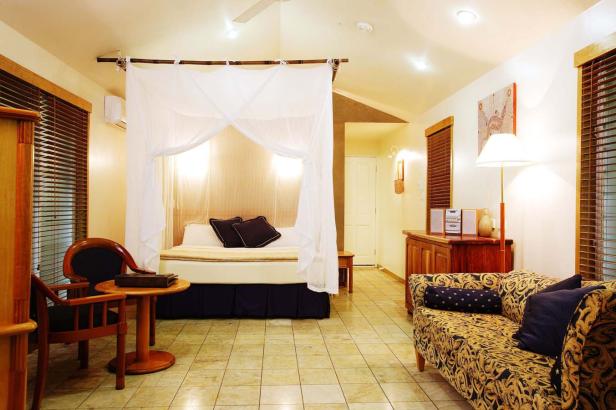 Ein Schlafzimmer mit Himmelbett, Sessel und gemusterter Couch.