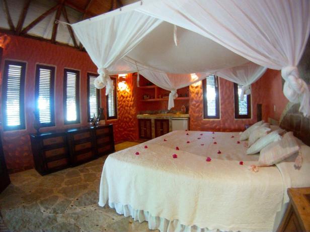 Ein Schlafzimmer mit Himmelbett und Rosenblättern auf der Bettdecke.