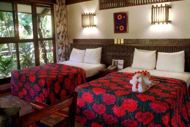 Ein Hotelzimmer mit zwei Betten und rot gemusterten Tagesdecken.