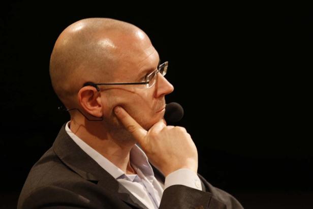 Ein Mann mit Brille und Mikrofon denkt nach.
