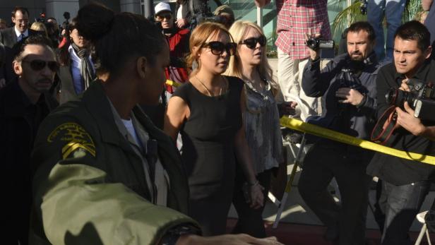 Lindsay Lohan wird von einem Sheriff des Los Angeles County begleitet, während Paparazzi Fotos machen.