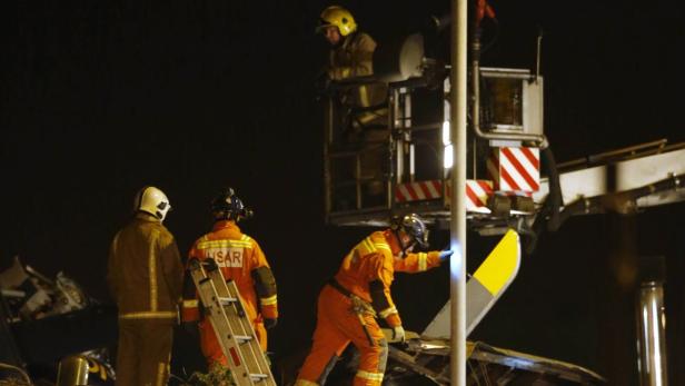 Mehrere Feuerwehrleute arbeiten nachts an einem Unfallort mit schwer beschädigten Fahrzeugen.