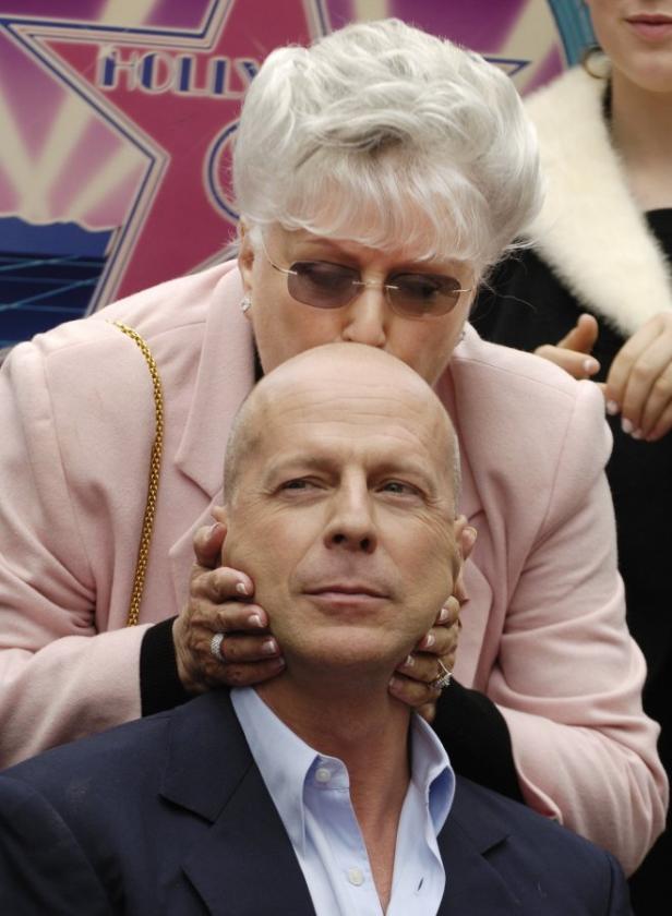 Eine Frau küsst Bruce Willis auf den Kopf.