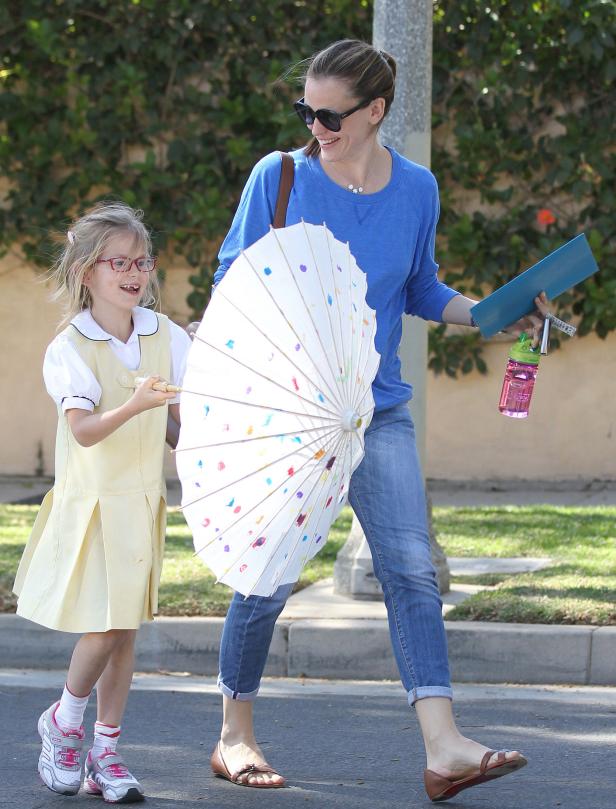 Jennifer Garner geht mit ihrer Tochter, die einen bemalten Sonnenschirm trägt, die Straße entlang.