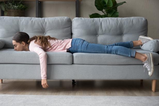 Frau liegt auf dem Bauch auf einer Couch.