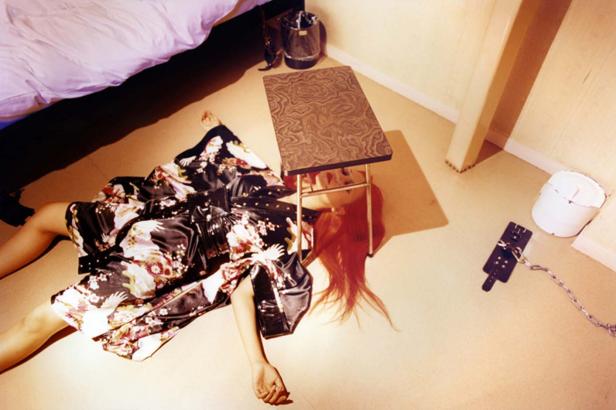 Eine Frau in einem Kimono liegt unter einem kleinen Tisch auf dem Boden.