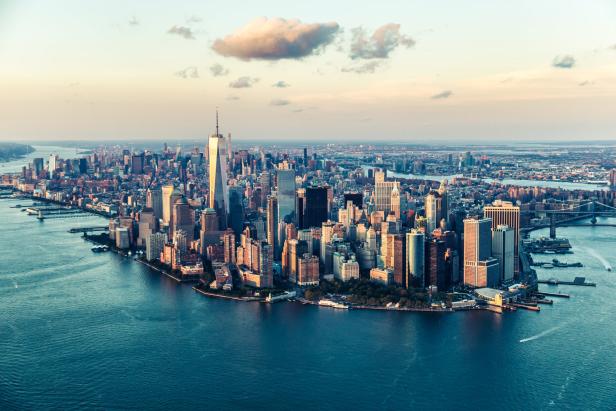 Luftaufnahme von Manhattan mit dem One World Trade Center im goldenen Abendlicht.