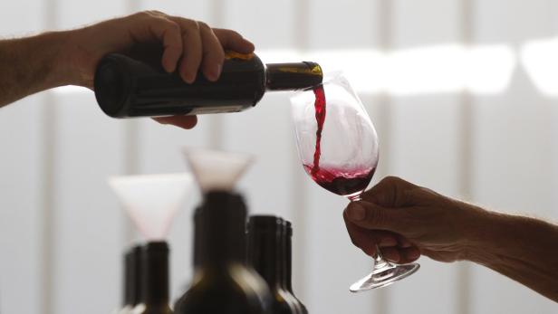 Eine Person gießt Rotwein in ein Glas.