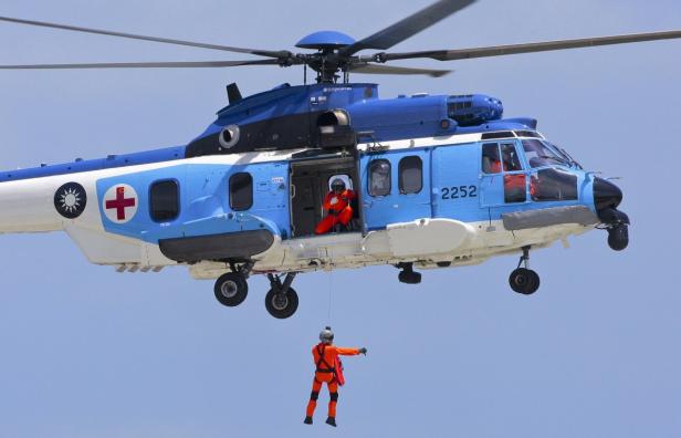 Ein Rettungshubschrauber mit einem Mann, der an einem Seil herabgelassen wird.