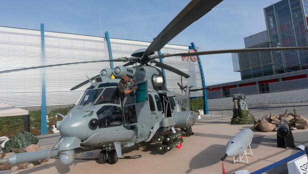 Ein grauer Militärhubschrauber steht auf einer Ausstellung mit einem Mann in der offenen Tür.