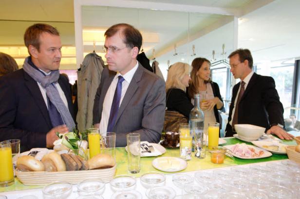 Mehrere Personen unterhalten sich an einem Tisch mit Speisen und Getränken.