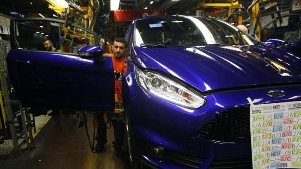 Ein Arbeiter montiert eine blaue Ford Fiesta in einer Fabrikhalle.