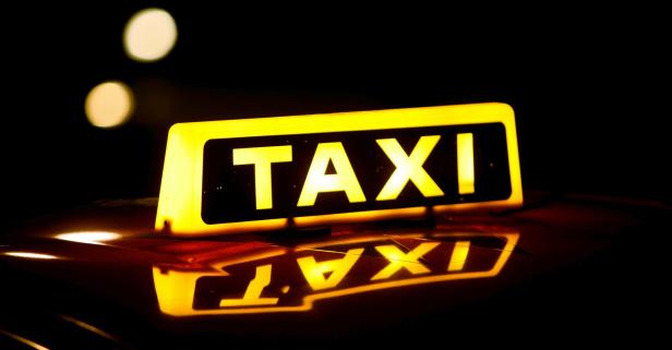 Ein gelbes Taxi-Schild leuchtet im Dunkeln.