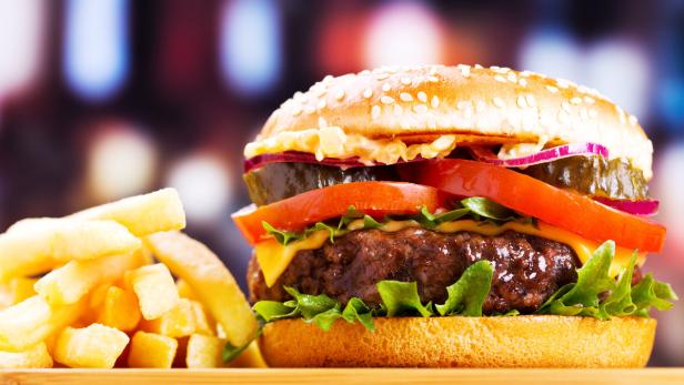 Ein appetitlicher Hamburger mit Pommes Frites auf einem Holztisch.