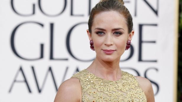 Emily Blunt bei den Golden Globe Awards mit einem goldenen Kleid und roten Ohrringen.