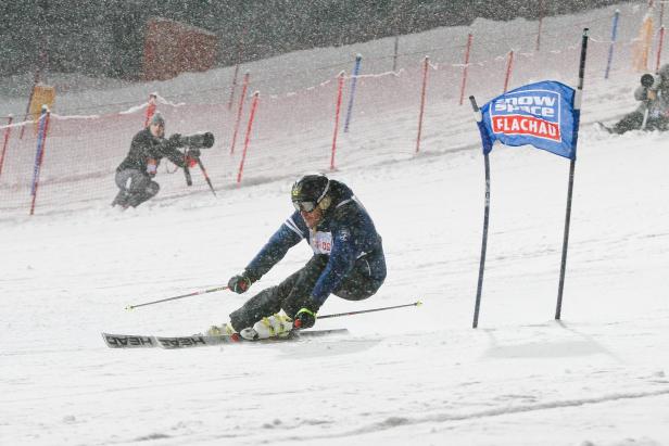 Ein Skifahrer fährt bei starkem Schneefall einen Hang hinunter.