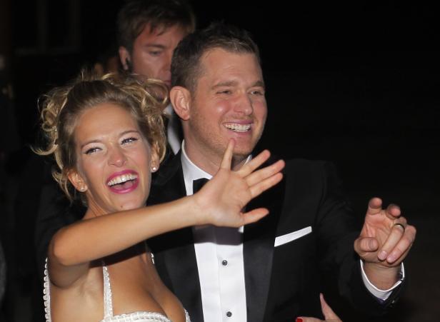 Michael Bublé und seine Frau Luisana Lopilato lächeln und winken in die Kamera.
