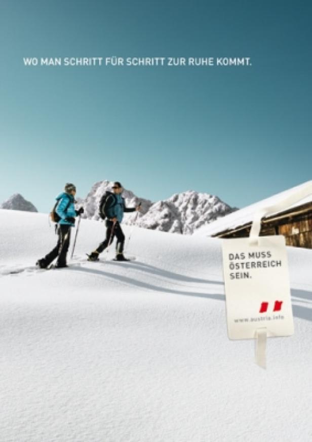 Zwei Personen wandern mit Schneeschuhen durch eine verschneite Winterlandschaft in Österreich.
