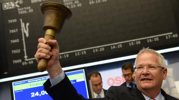 Ein Mann läutet die Börsenglocke vor einer Anzeigetafel mit dem DAX-Index.