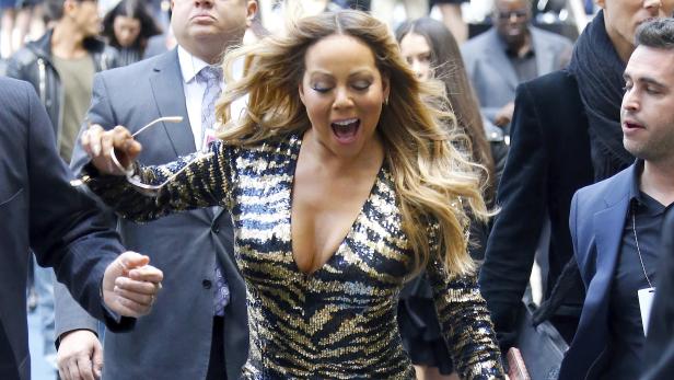 Mariah Carey in einem Paillettenkleid, umringt von Bodyguards.