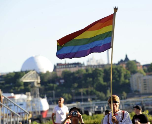 Eine Person hält eine Regenbogenflagge in Stockholm.