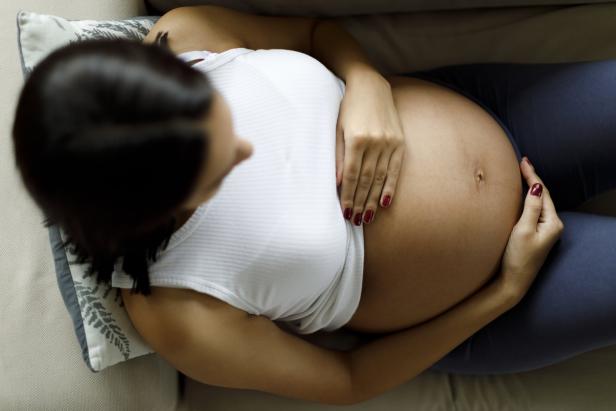 Eine schwangere Frau greift sich auf den Bauch.