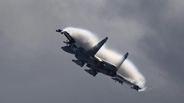 Ein Kampfjet zieht Kondensstreifen vor einem grauen Himmel.