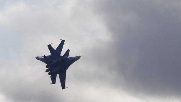 Ein blaues Kampfflugzeug fliegt vor einem bewölkten Himmel.