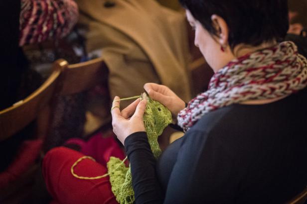 Eine Frau strickt mit hellgrüner Wolle an einem Kleidungsstück.