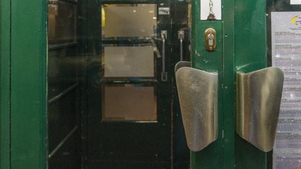 Eine grüne Tür mit silbernen Griffen und einem Aushang.